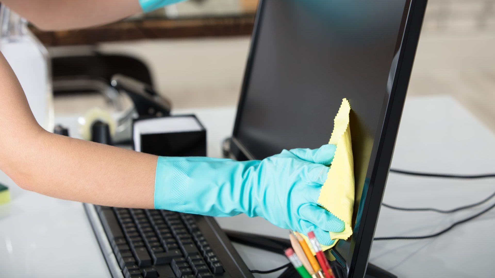 A person is cleaning a computer monitor with a cloth.