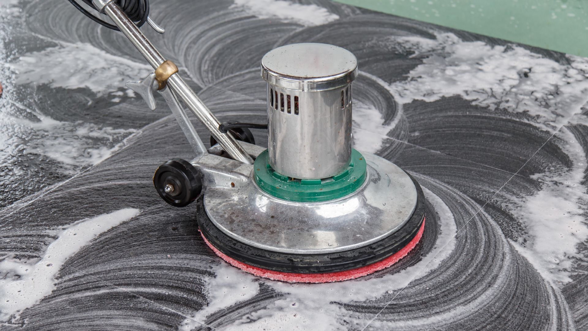 A person is cleaning a tile floor with a machine.