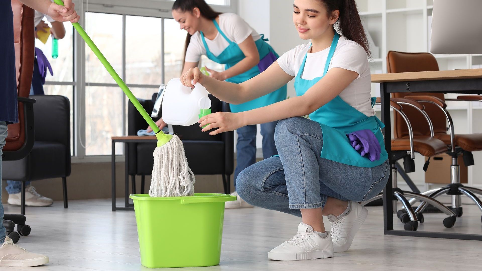 A group of cleaners are cleaning an office with mop and bucket.