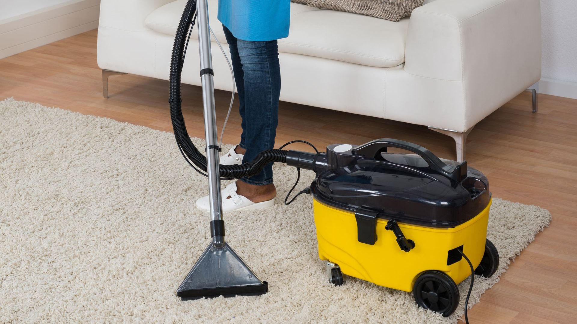 A person is using a vacuum cleaner to clean a rug in a living room.