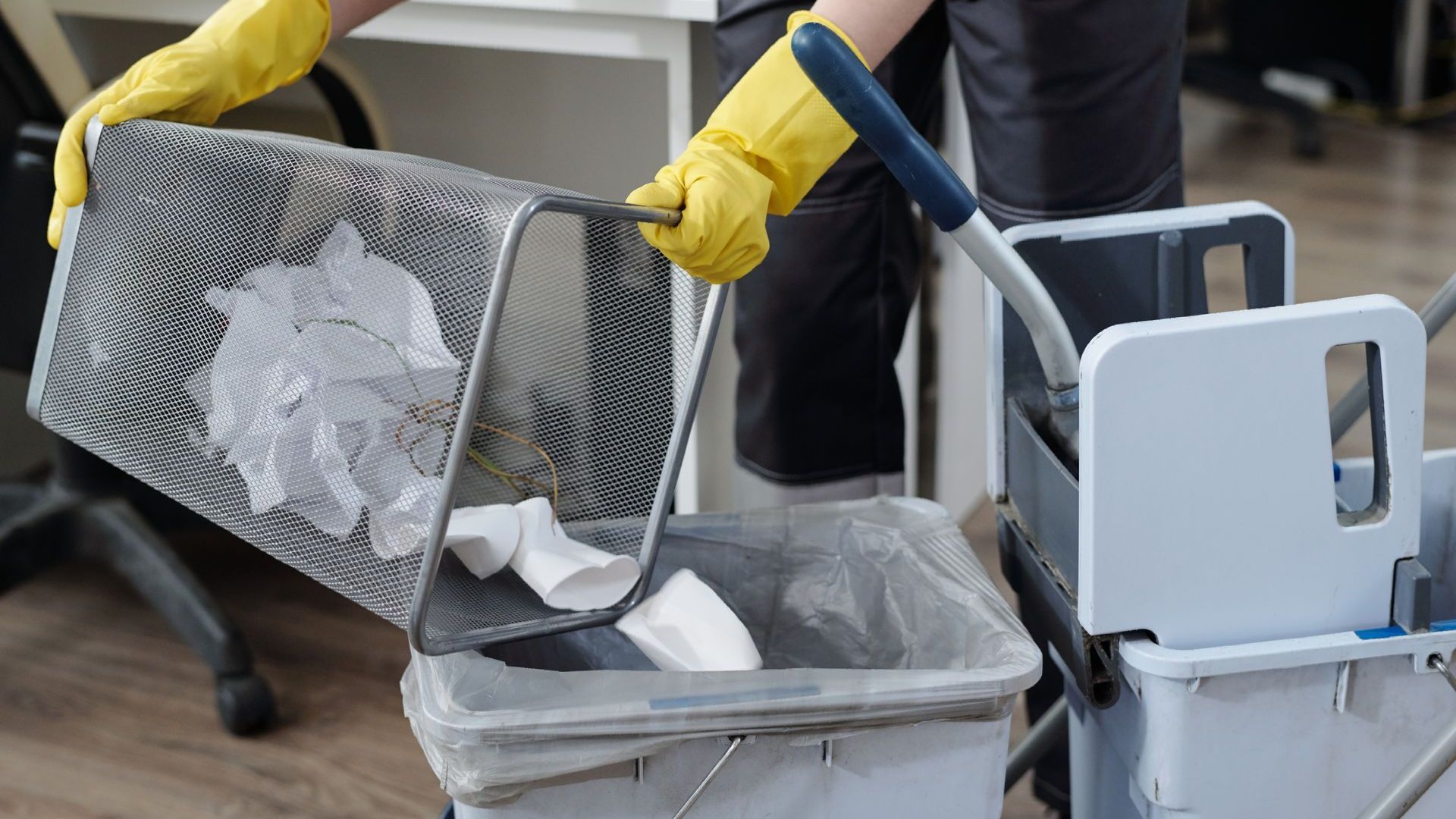 A person wearing yellow gloves is cleaning an office.