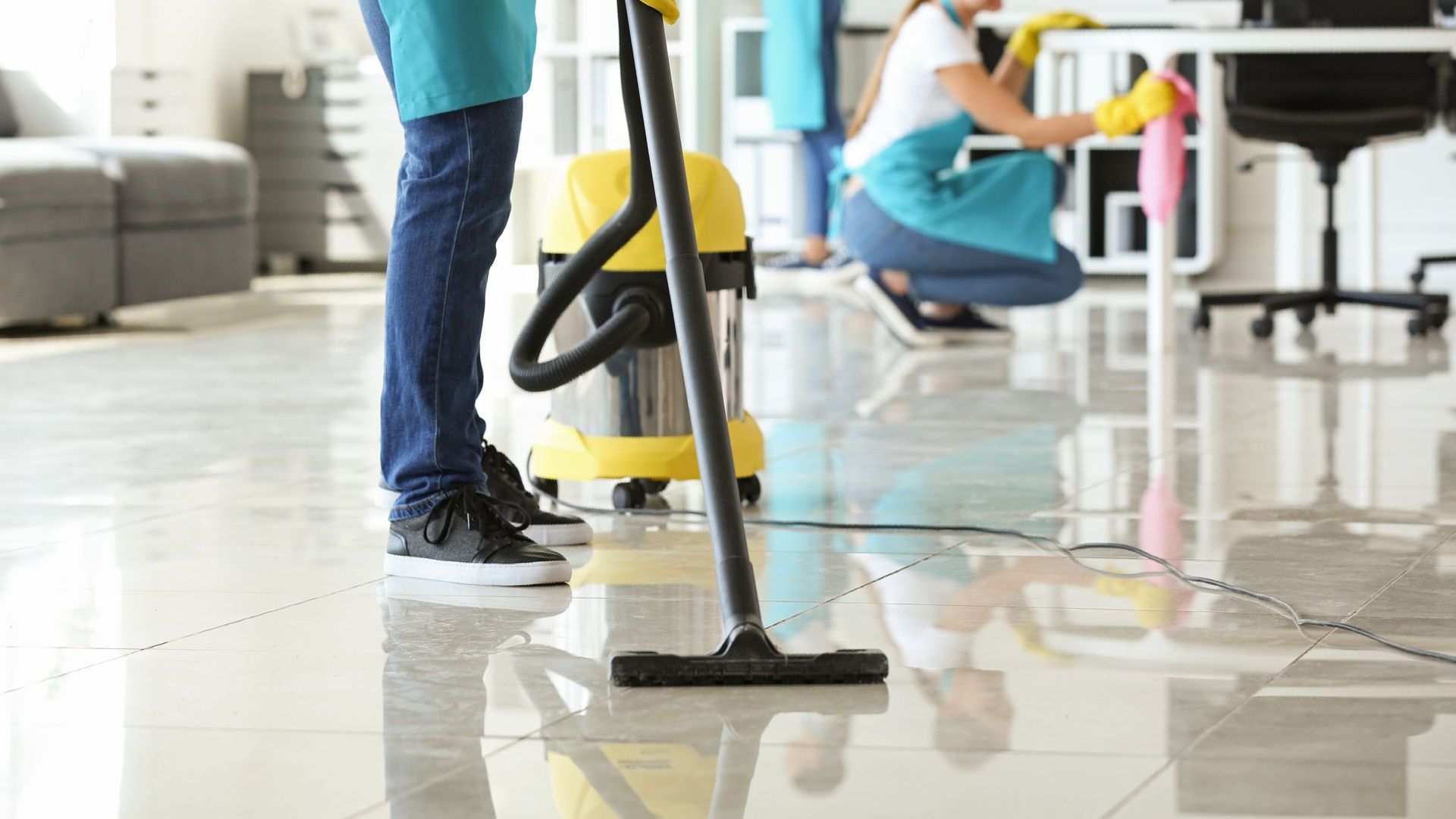 A man is using a vacuum cleaner to clean the floor in an office.