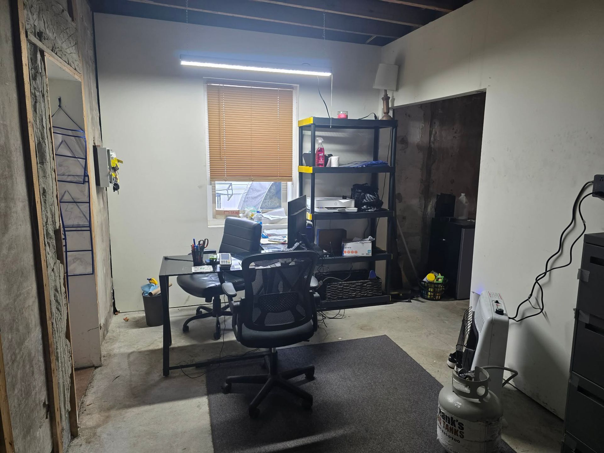 Office space with desk, chair, window, shelves, and unfinished walls. | Seth's Auto Care