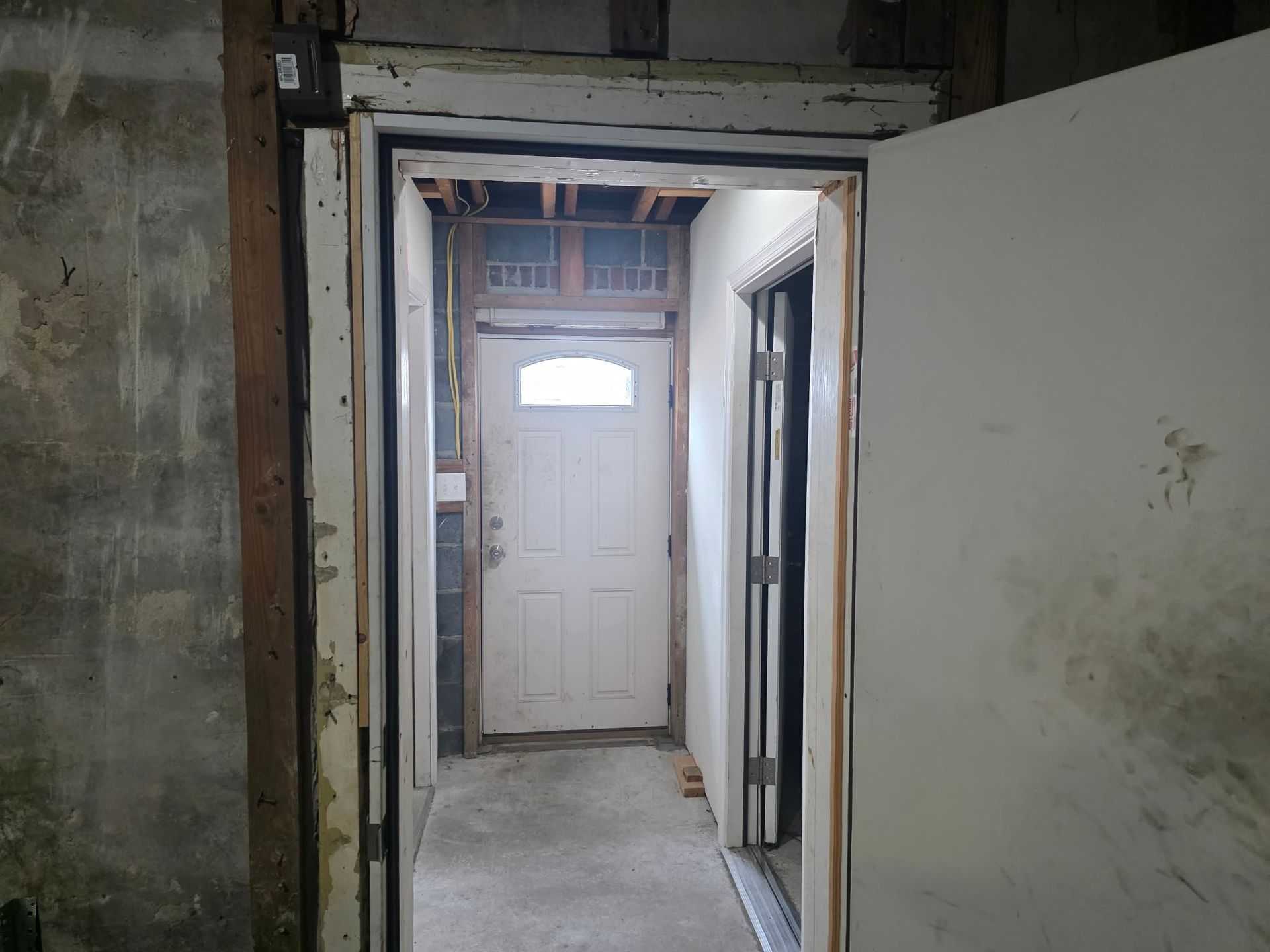 Hallway interior with exposed walls and a white door at the end. An open door is on the right. | Seth's Auto Care