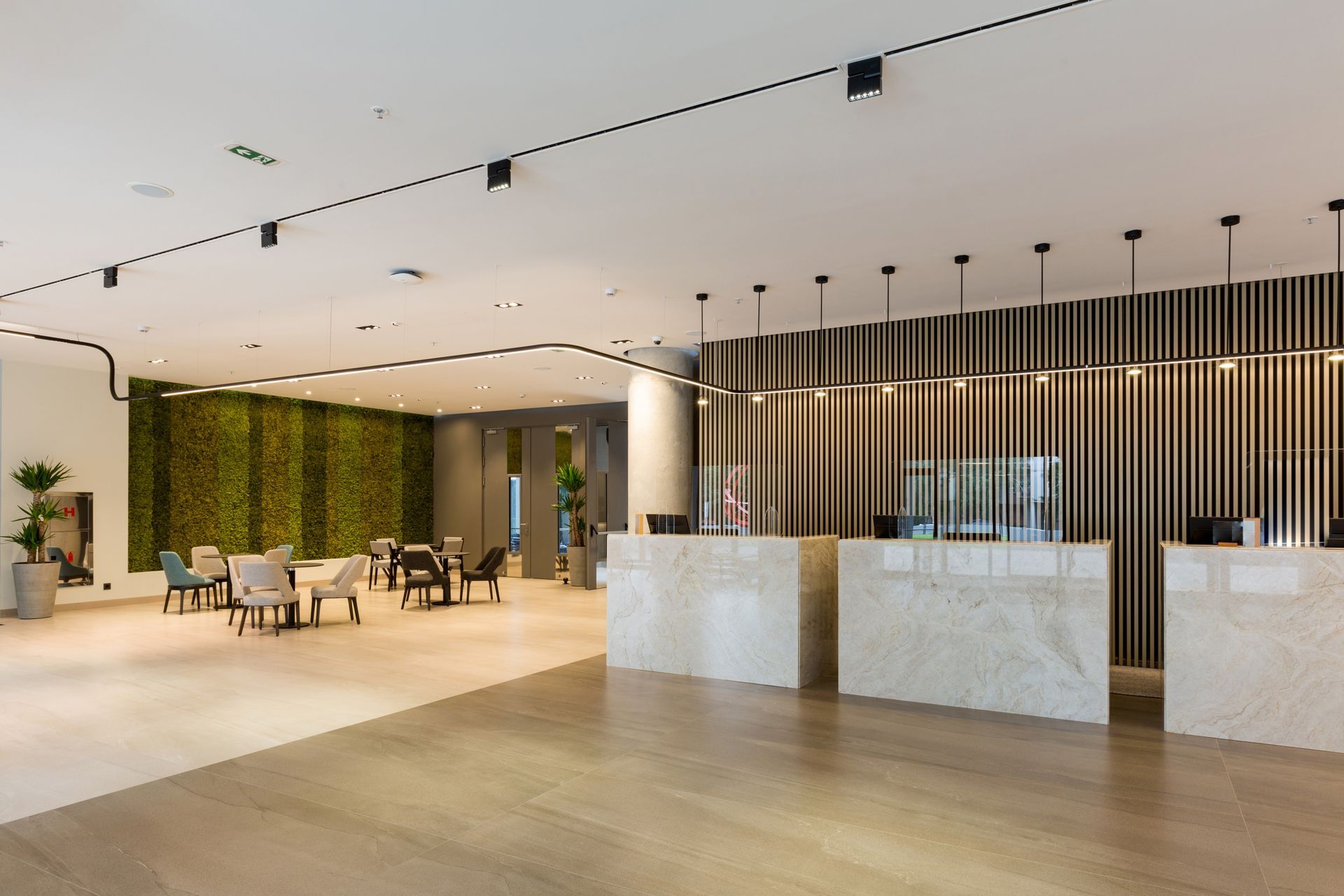 A large lobby with a row of reception desks and tables.