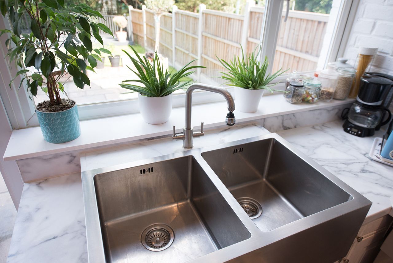 A kitchen sink is sitting on a counter next to a window.