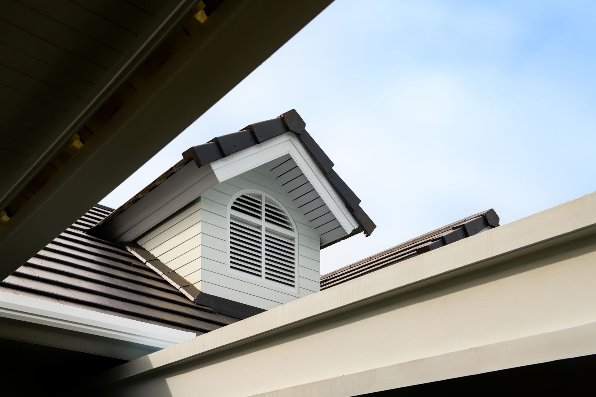 Looking up at the roof of a house with a window.