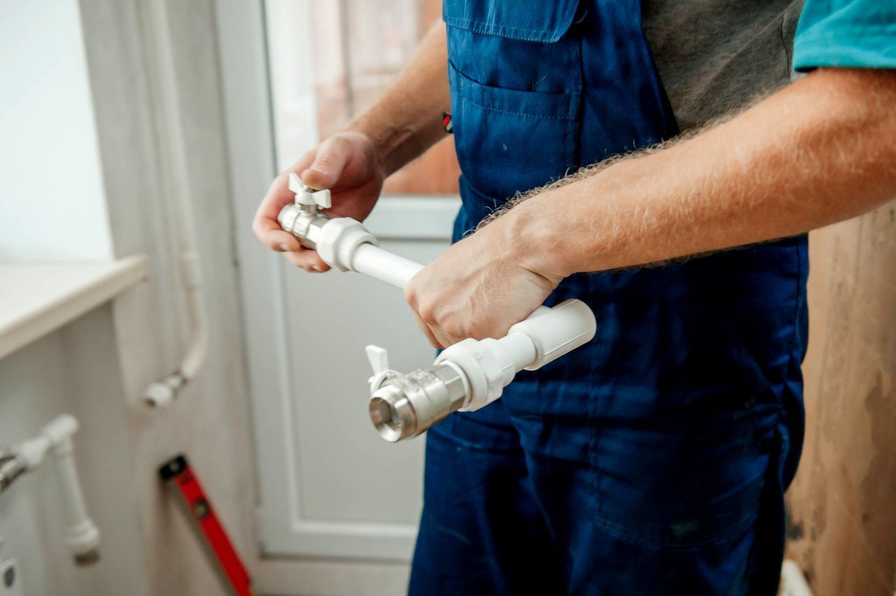 A plumber is fixing a pipe in a bathroom.