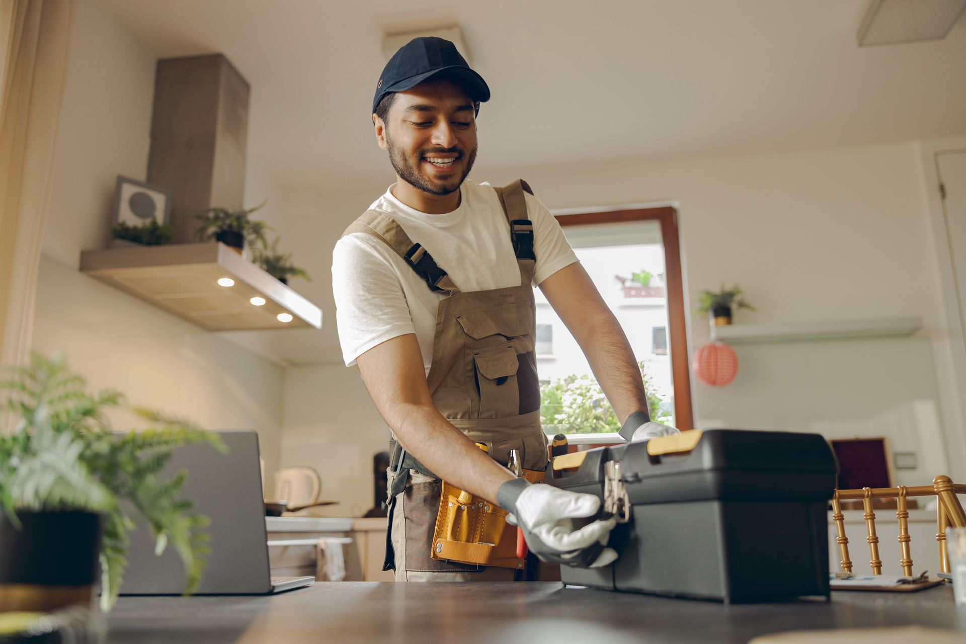 Worker in a workshop smiling while using a power tool at a workbench