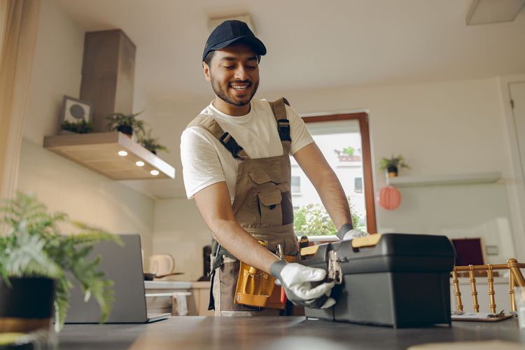 Worker in a workshop smiling while using a power tool at a workbench