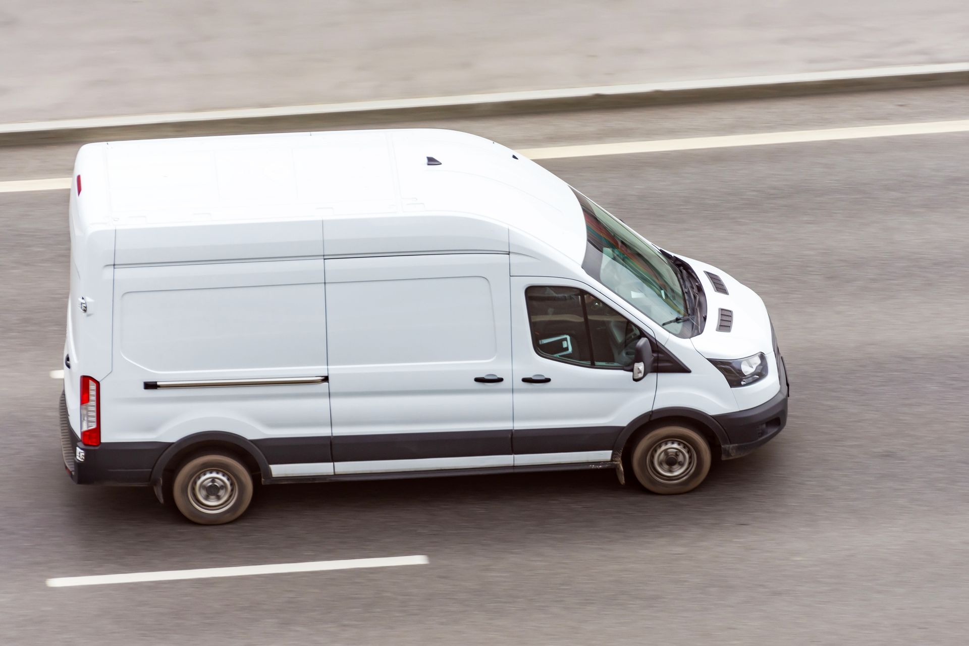 A white van is driving down a road.