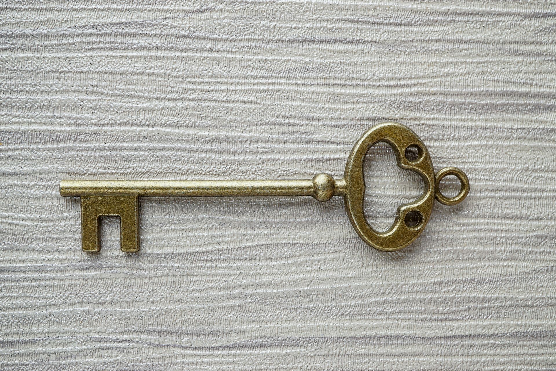 A close up of a brass key on a wooden surface.
