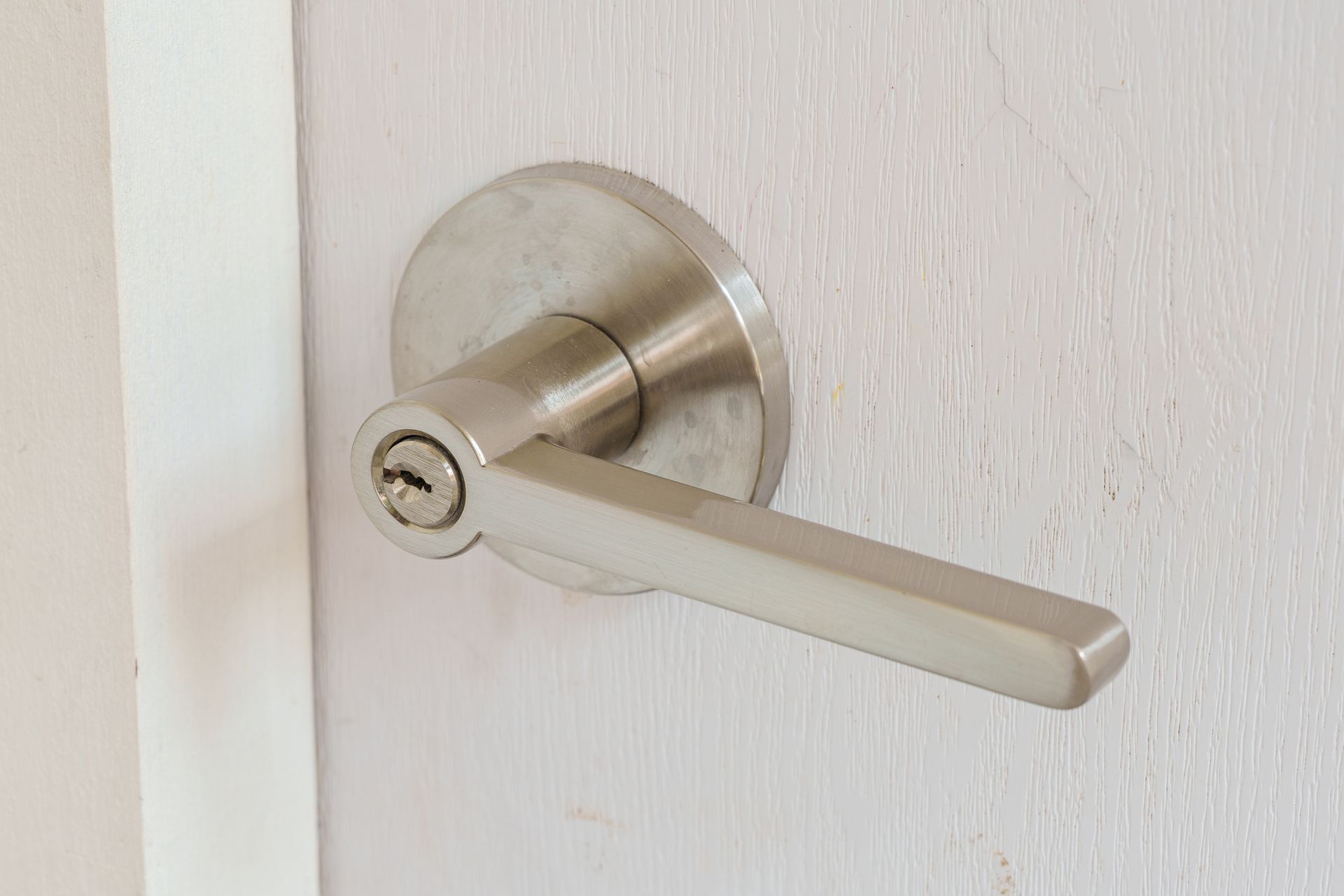 A close up of a door handle on a white door.