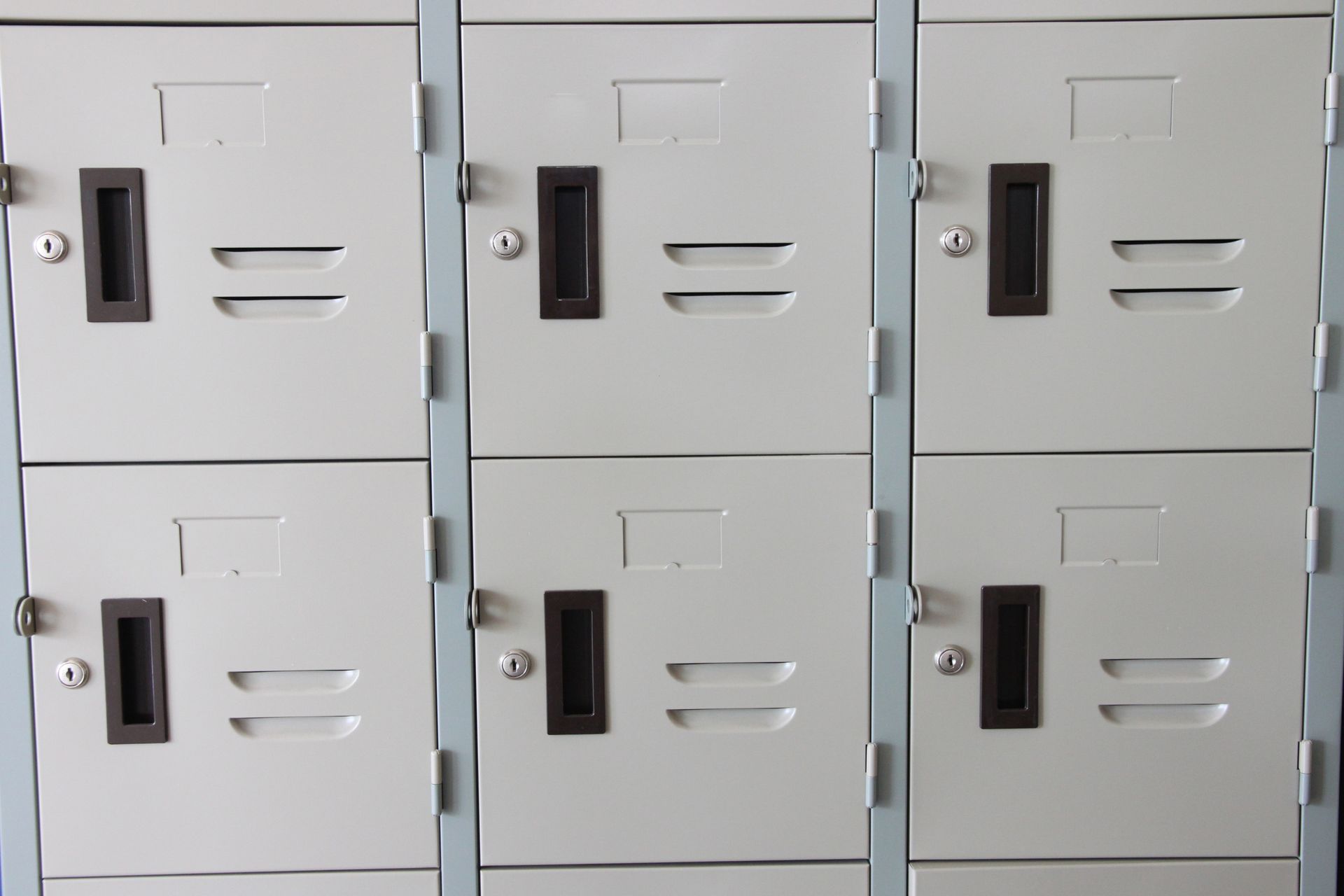 A row of white lockers with black handles and keys