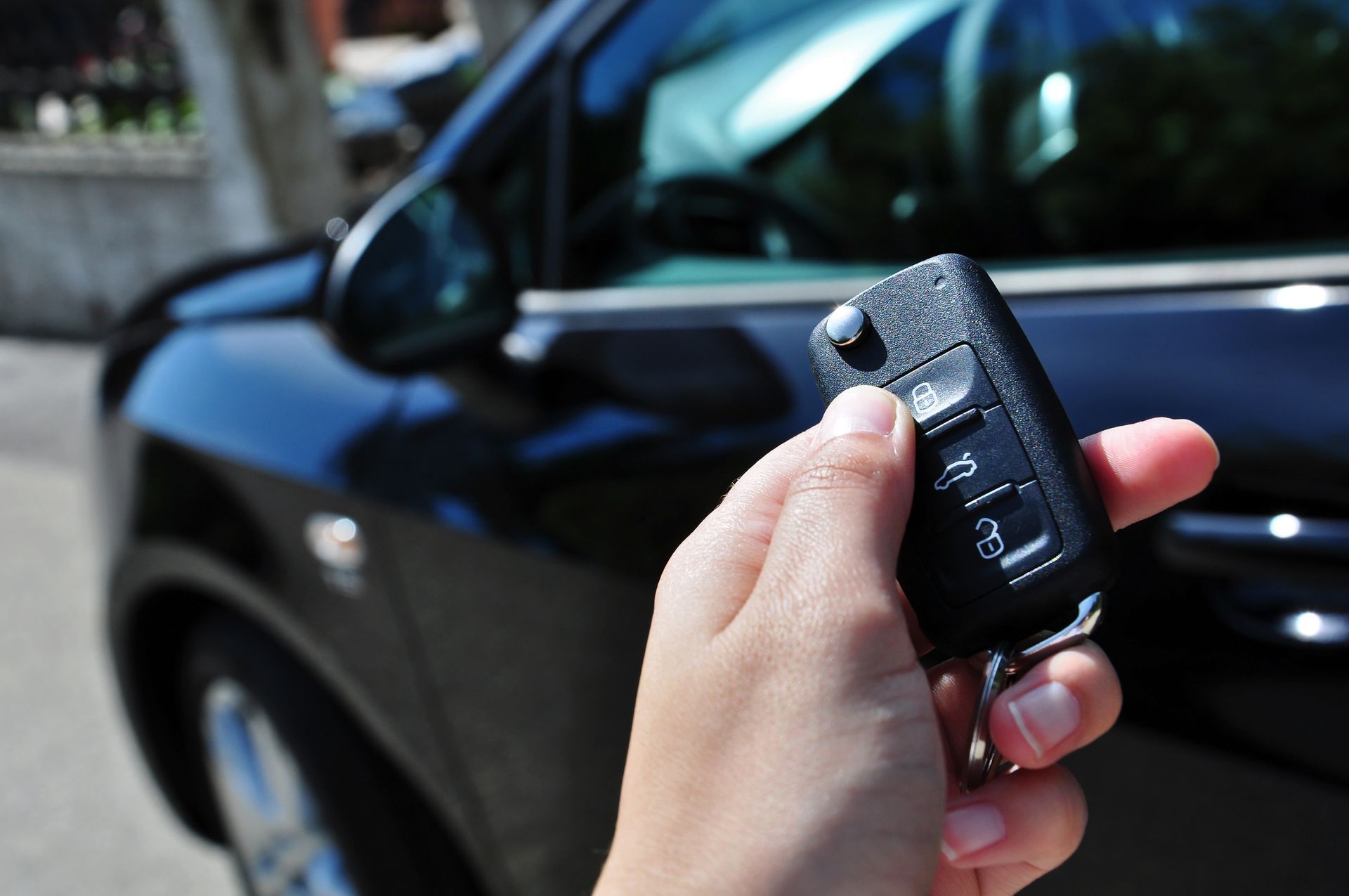 A person is holding a car key in front of a car