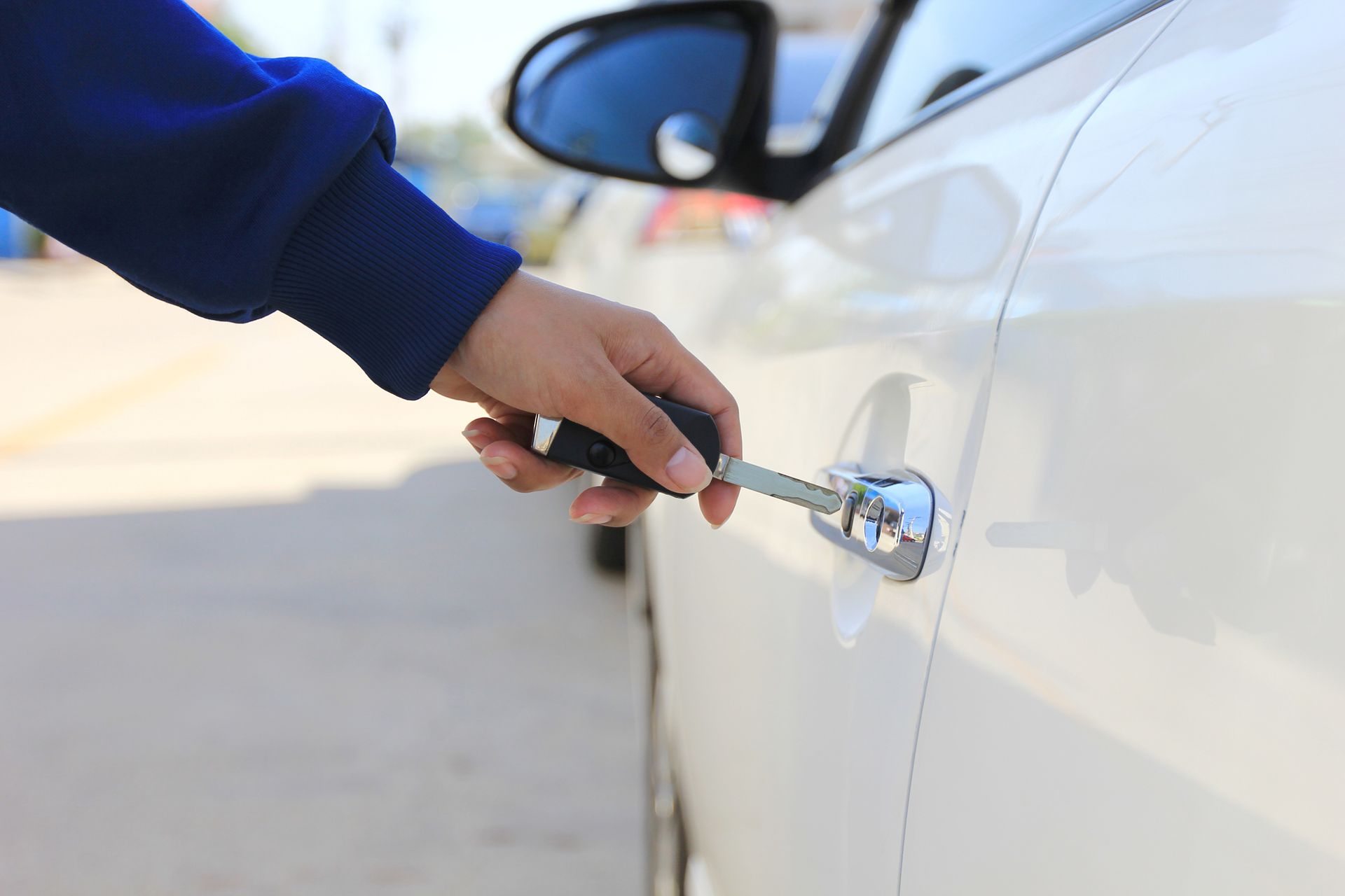 A person is opening a car door with a key.