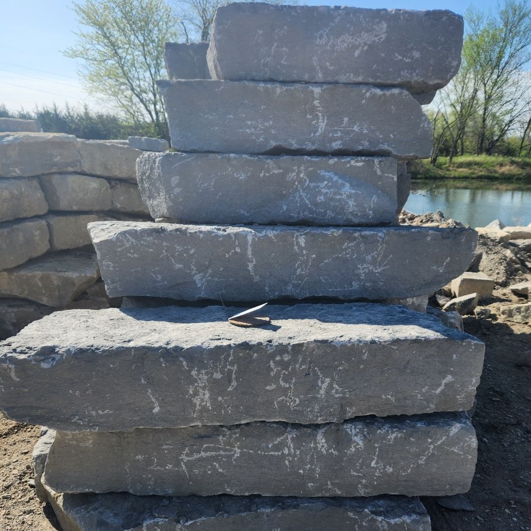 A pile of bricks stacked on top of each other in front of a body of water.