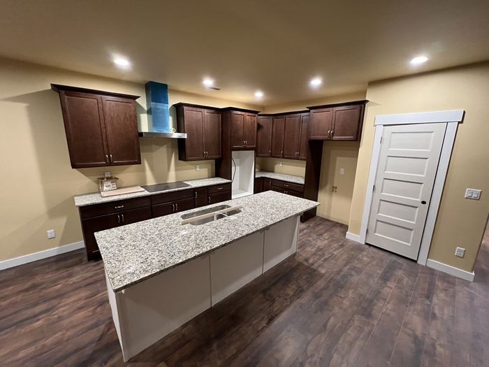 Modern kitchen with dark brown cabinets, large island, and wood floors.