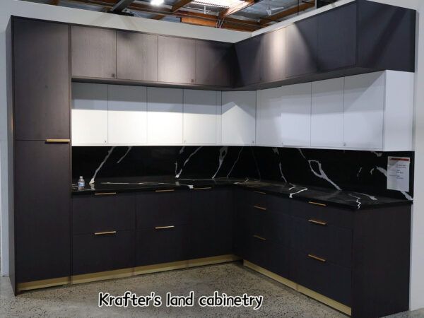 Modern kitchen cabinetry in dark gray with gold accents and a marble backsplash.