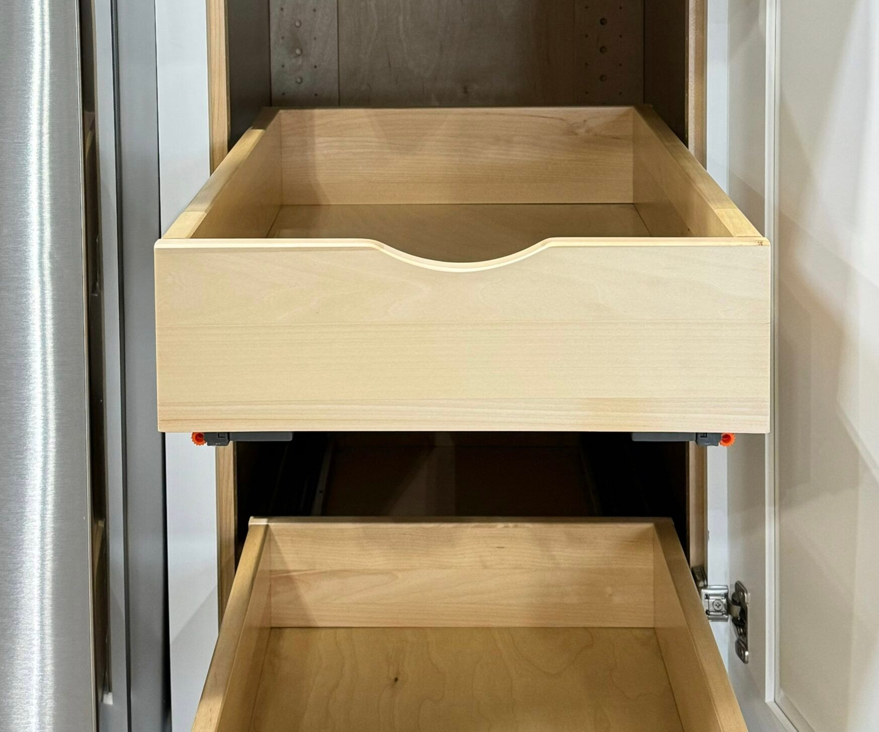 Two open wooden drawers inside a cabinet. The top drawer has a curved cutout.