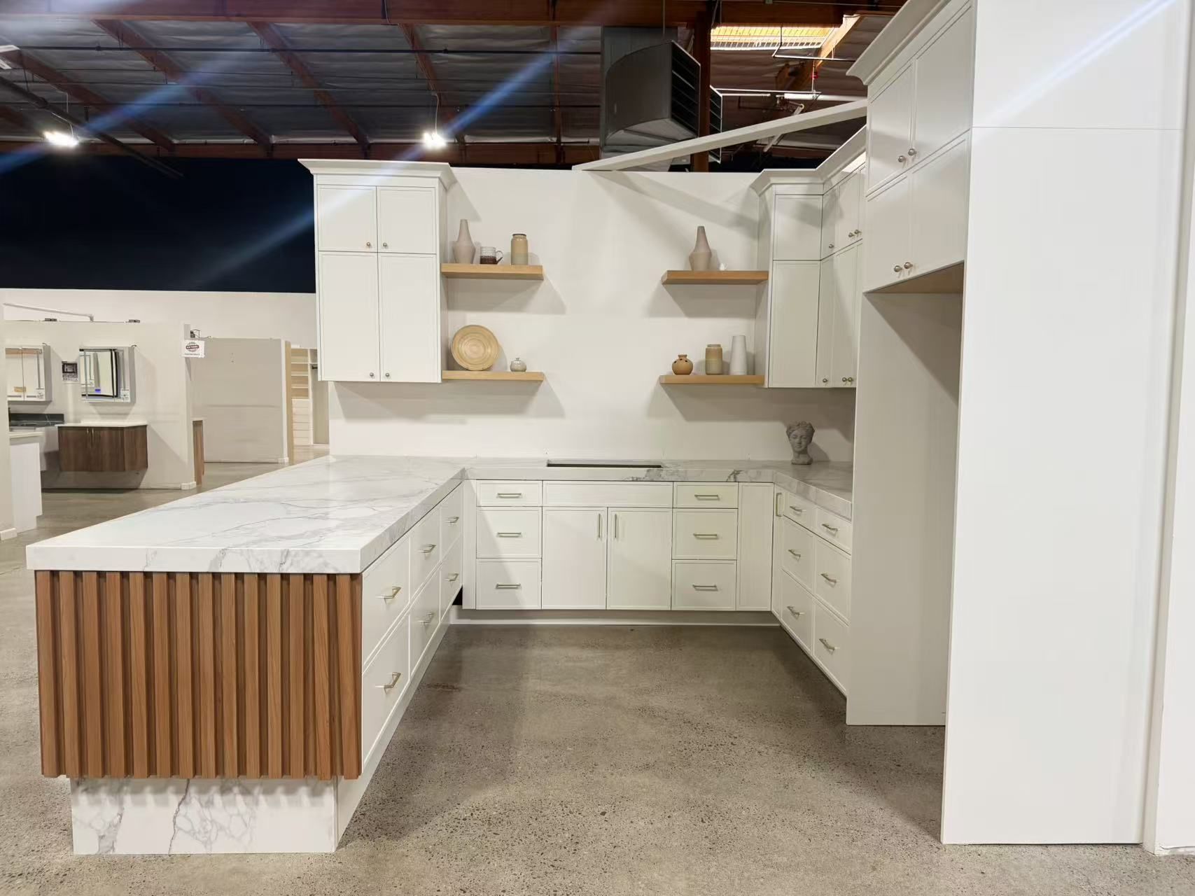 White kitchen display with wooden island accents and floating shelves.