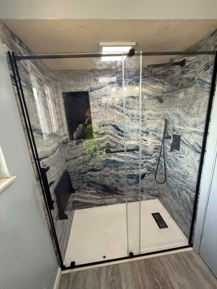 Glass shower enclosure with white marble walls and black trim in a modern bathroom
