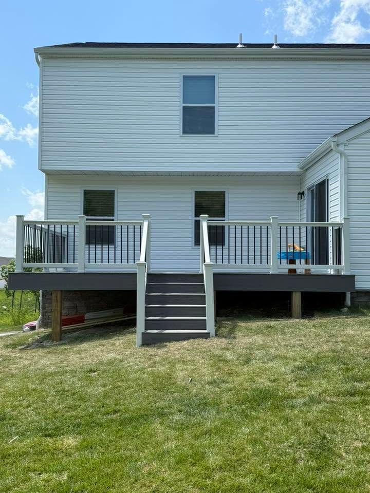 Backyard view of a raised white house with a central staircase and side decks