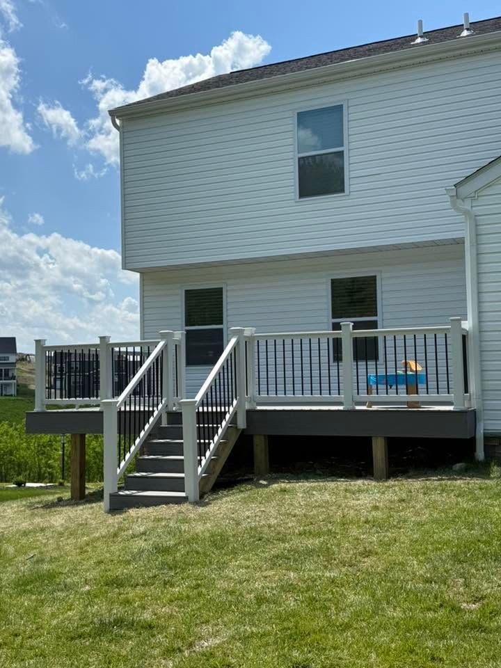 Backyard deck with stairs on a white two-story house under a blue sky