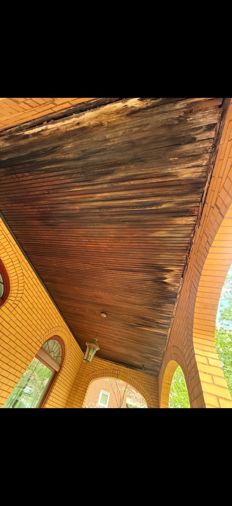 Close-up of a wooden arched ceiling with warm brown grain and brick pillars below