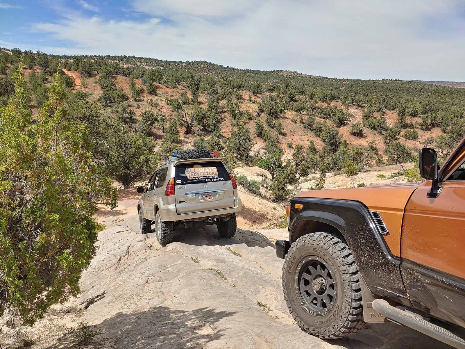 Two off road vehicles are driving down a dirt road.