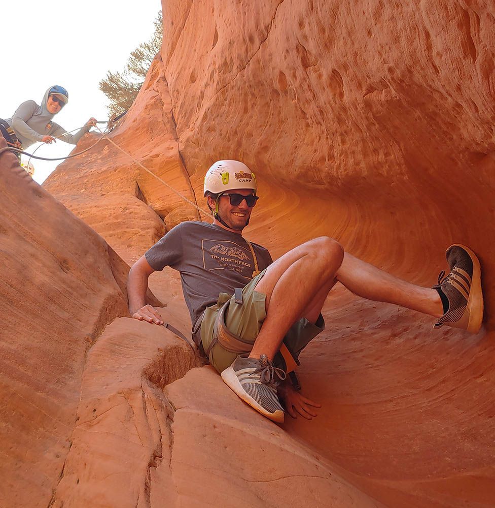 A man wearing a helmet is laying on a rock