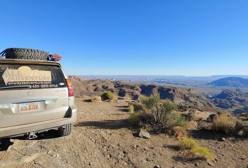 A dusty car is parked next to the canyon's edge