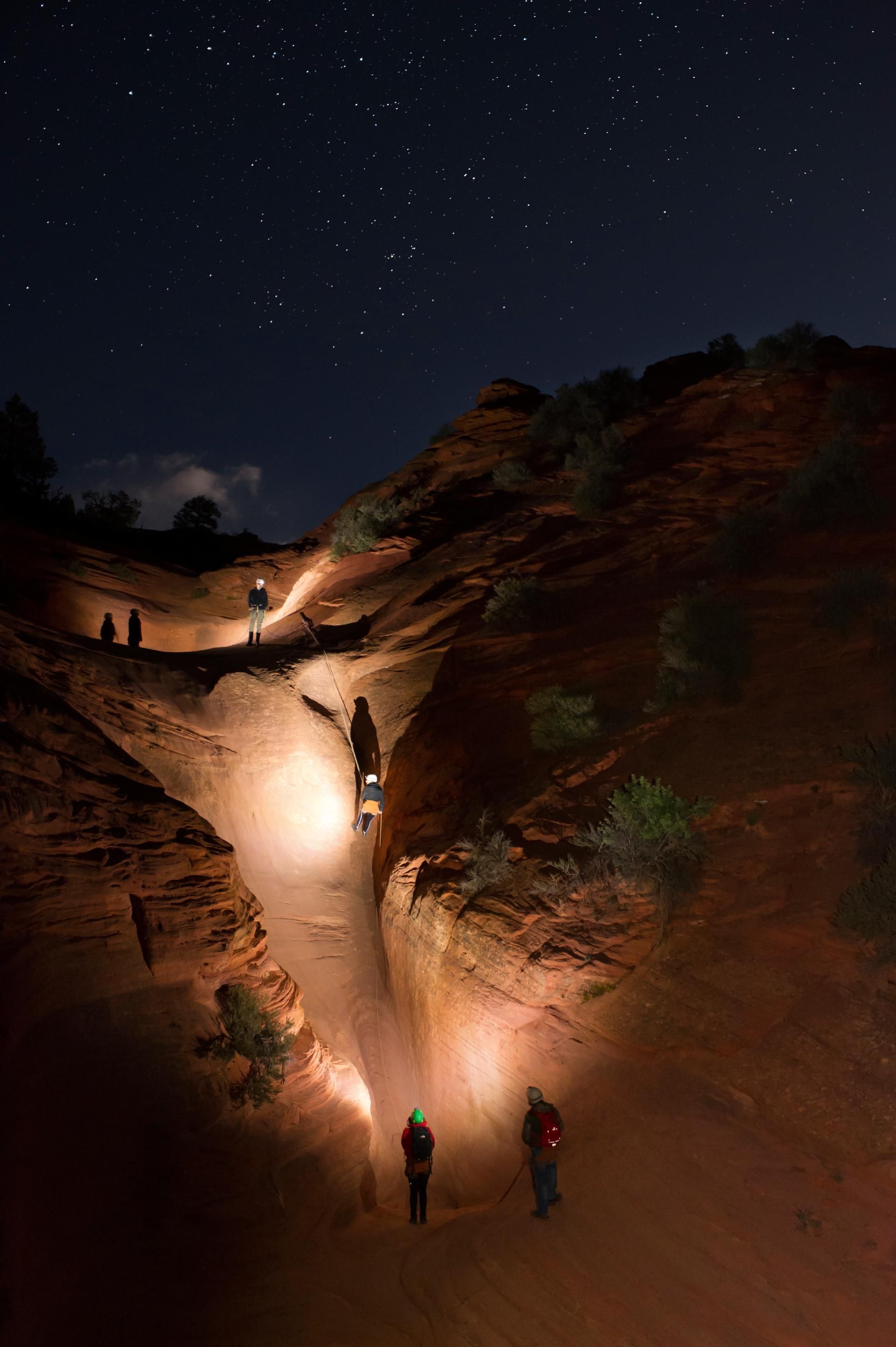 A group of people are walking down a canyon at night.