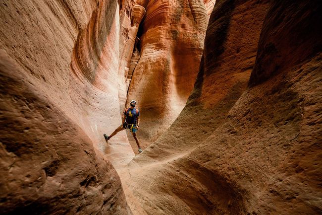 Ladder Canyon, East Zion Utah A guest is posing in a stunning red rock slot canyon in Ladder Canyon near Zion National Park, guided by a professional from All Ways Adventure.