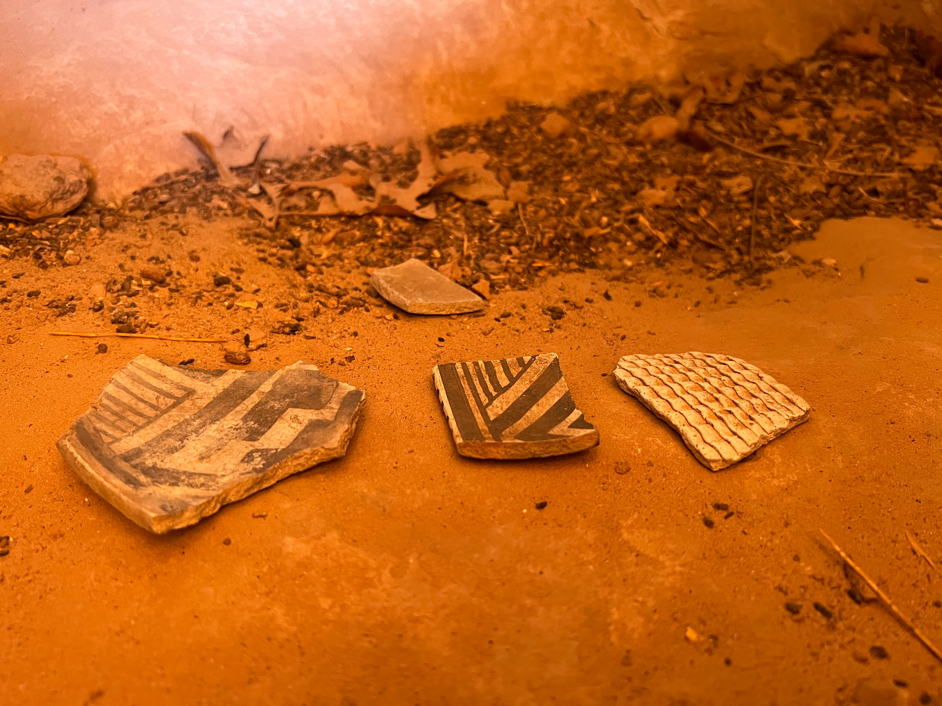 Three pottery shards with black and white geometric designs on reddish ground.