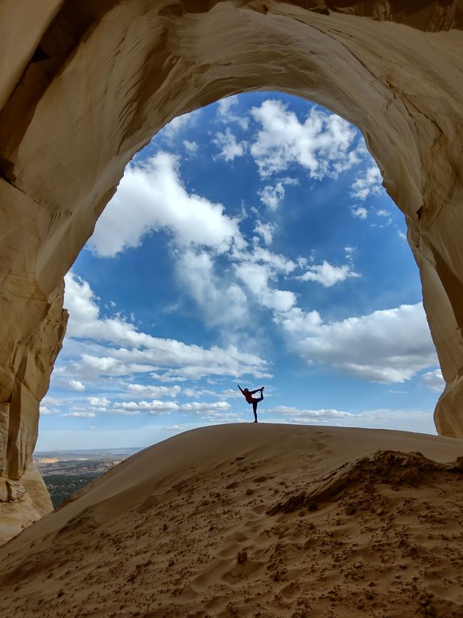 A hiker poses in the grandness of the Great Chamber A person standing inside the massive, sun-lit Great Chamber alcove near Kanab, Utah, during a private All Ways Adventure off-road tour.