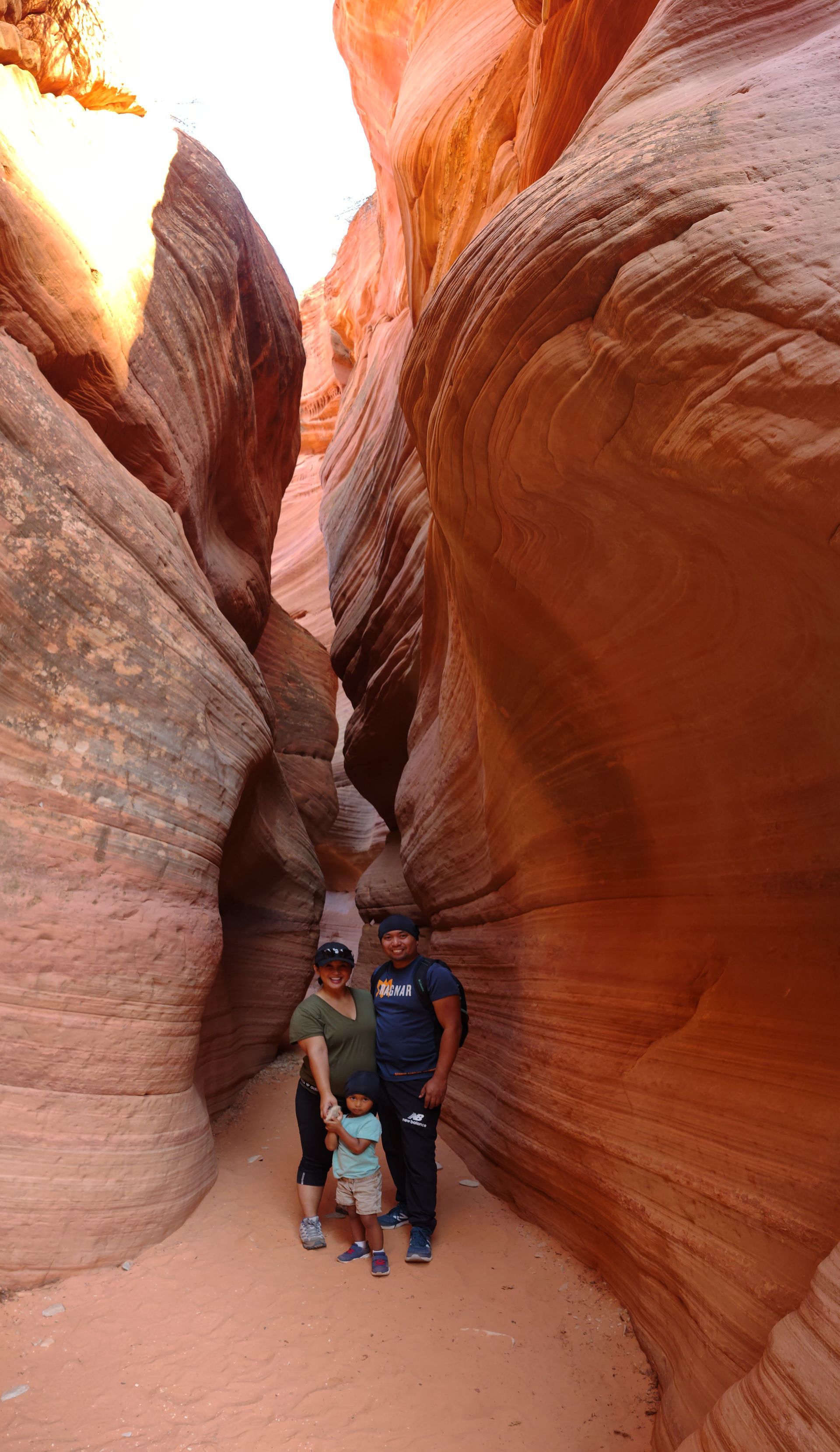 A hiker poses in the grandness of the Great Chamber The glowing, orange sandstone walls of Peek-A-Boo Slot Canyon near Kanab, Utah, during a private guided tour with All Ways Adventure.