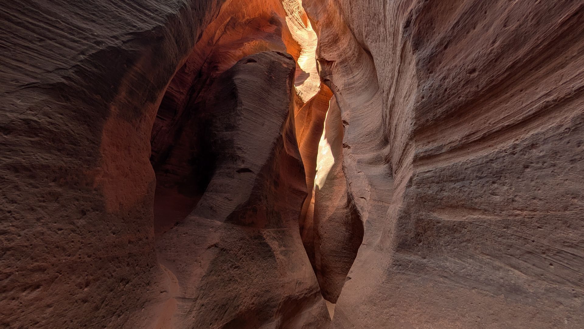A sandstone canyon with light streaming from above, illuminating the curved walls.