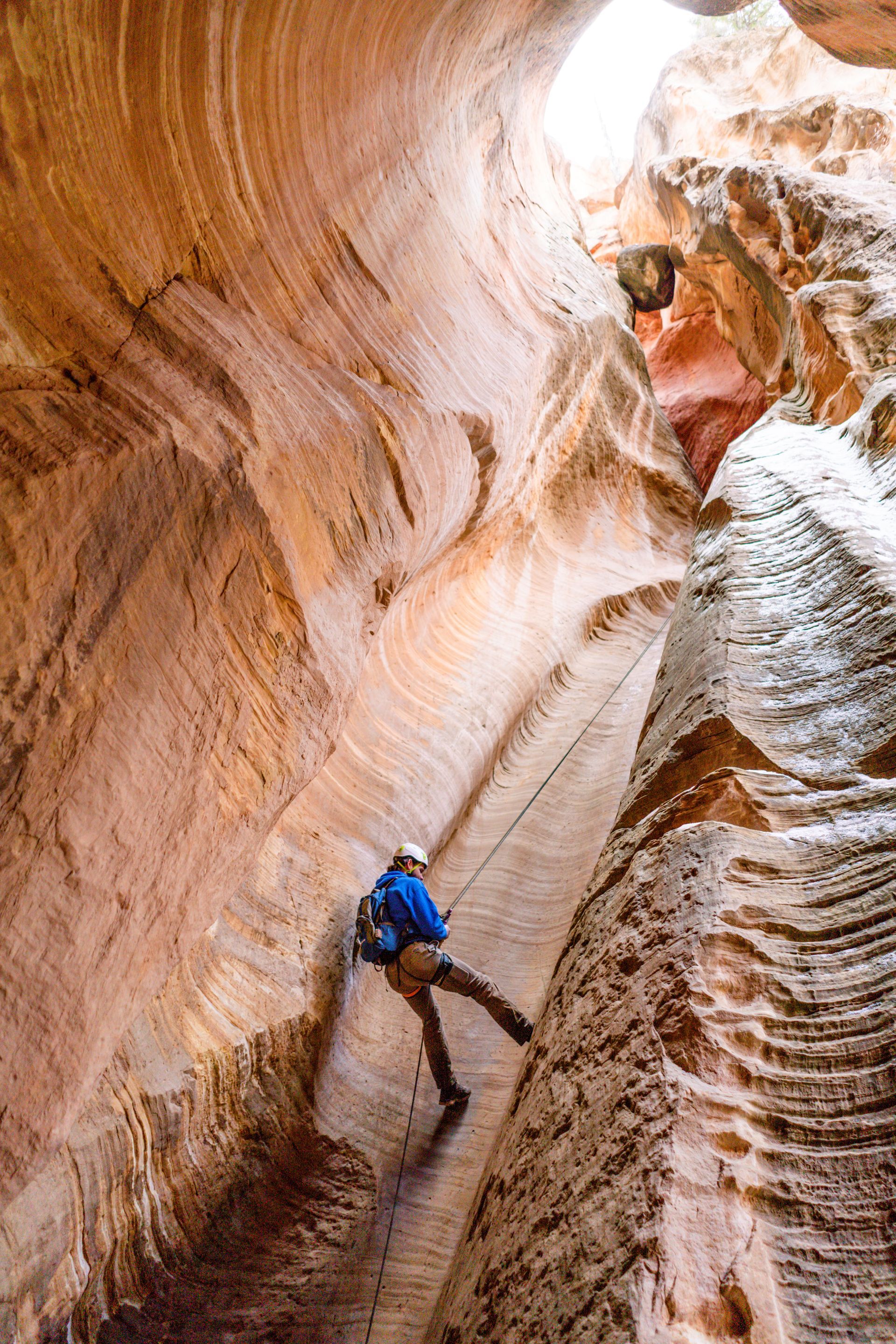 A person is climbing up a rock wall in a canyon.