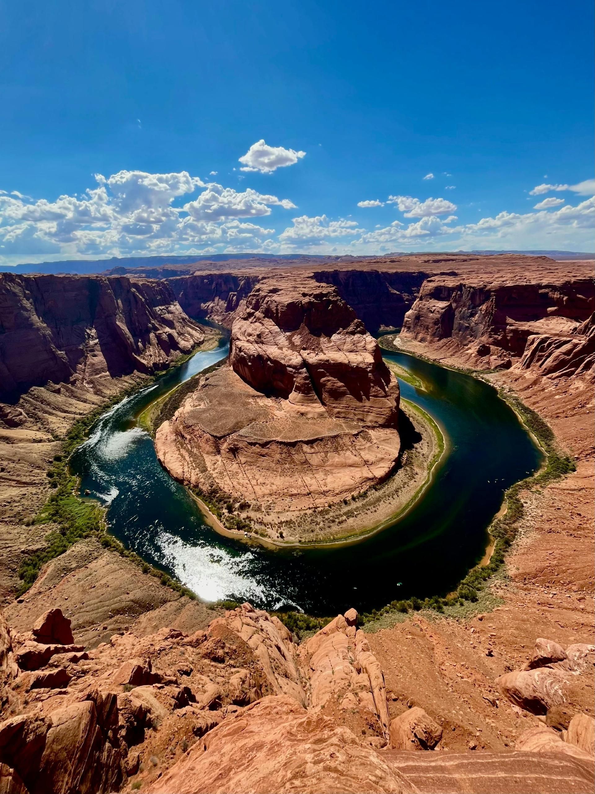 Horseshoe Bend in Arizona: a scenic overlook of a river curving around a sandstone butte under a blue sky.