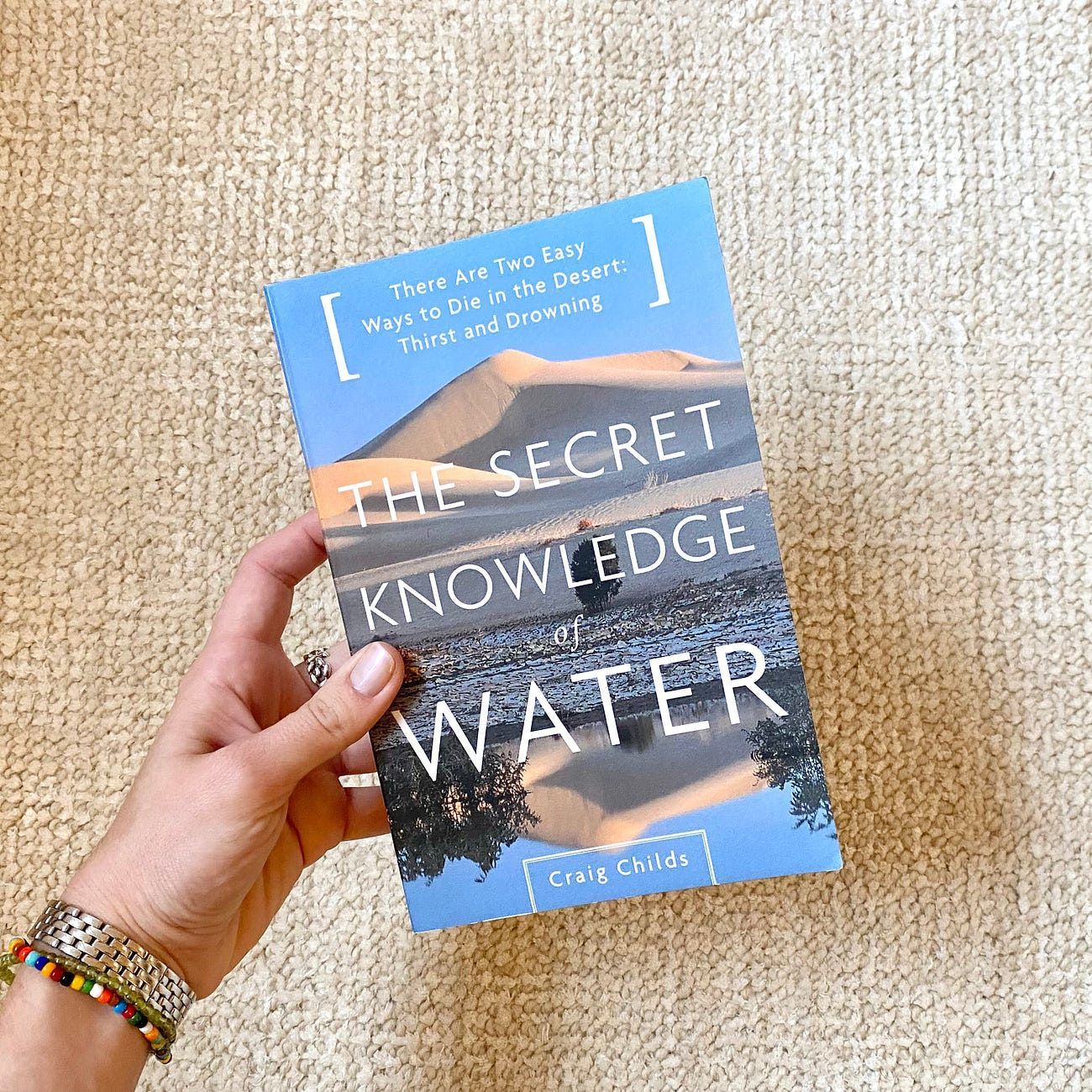 A person's hand holds a book titled 