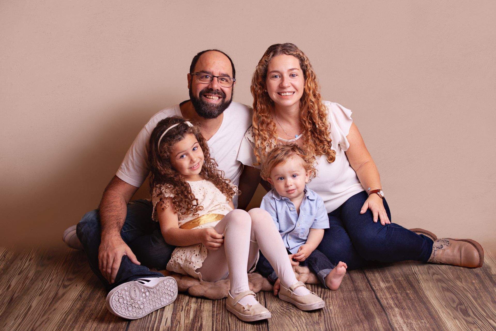 Una familia está sentada en el suelo posando para una fotografía.