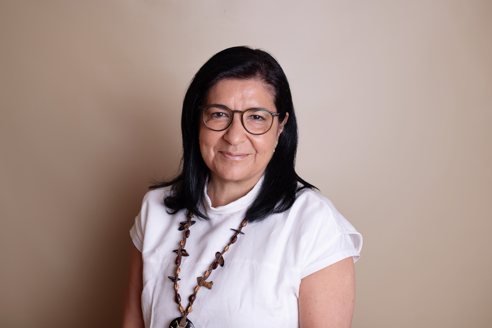Una mujer que lleva gafas y un collar sonríe para la cámara.