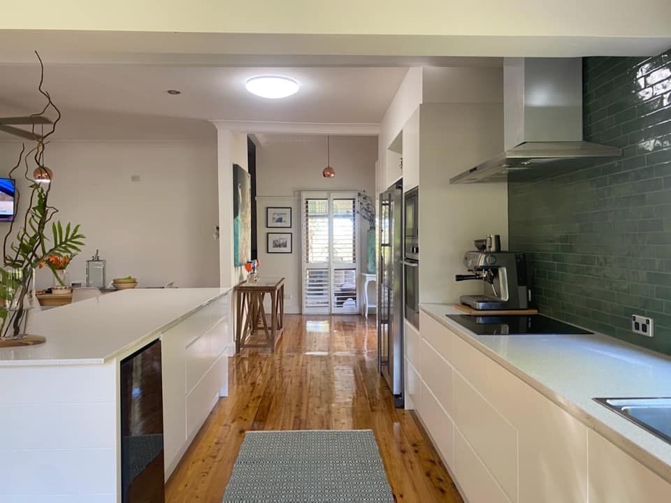 Kitchen With A Wooden Floor And White Cabinets — Lake Macquarie Designer Kitchens In Buttaba, NSW
