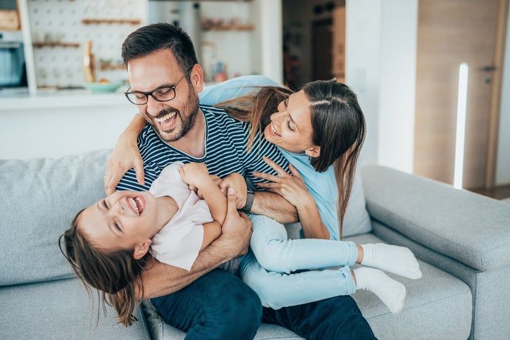 family laughs on the couch and are protected by life insurance
