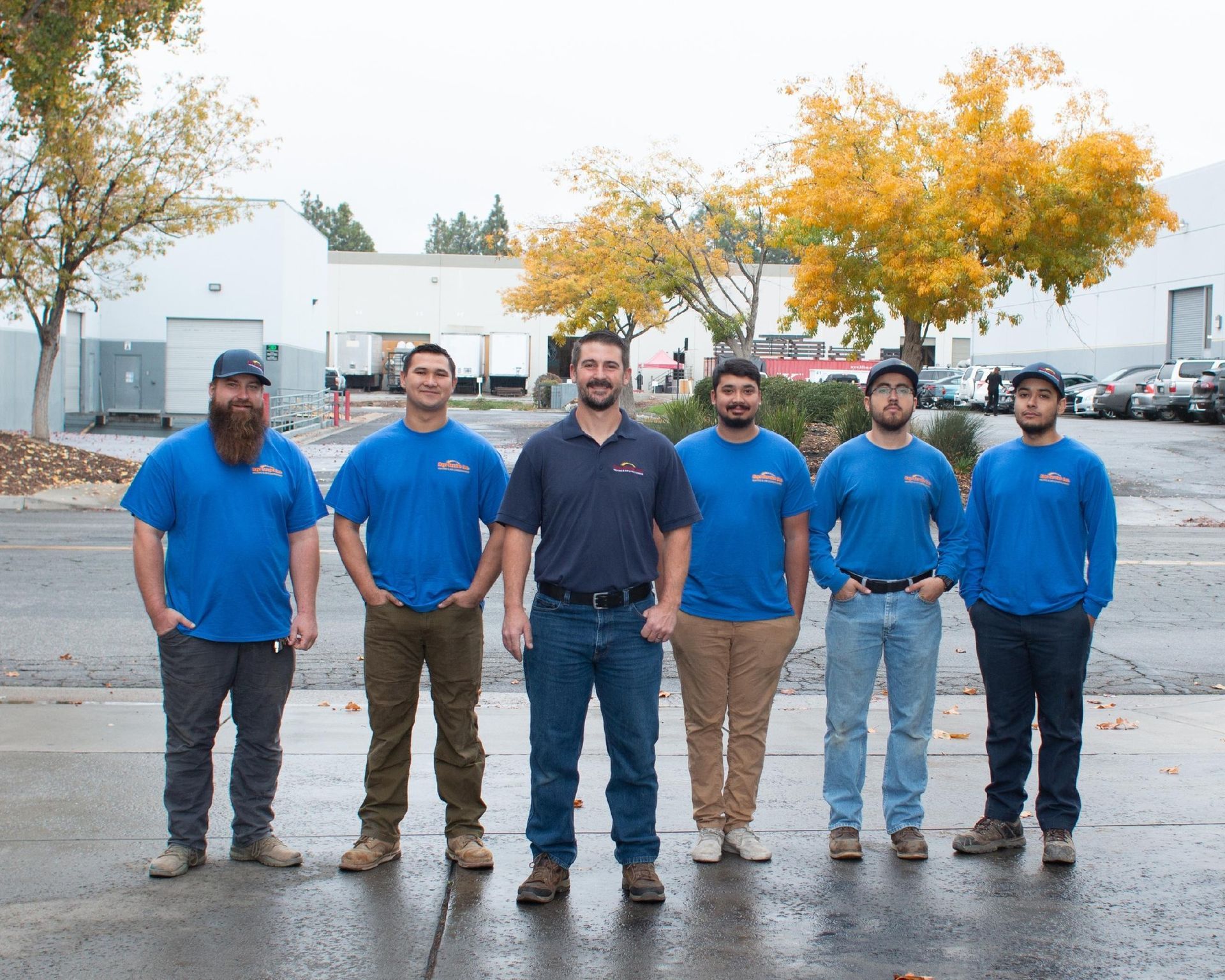 A group of men in blue shirts are posing for a picture