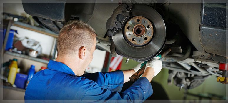 Brake Repair: A man is working on a brake disc on a car in a garage.