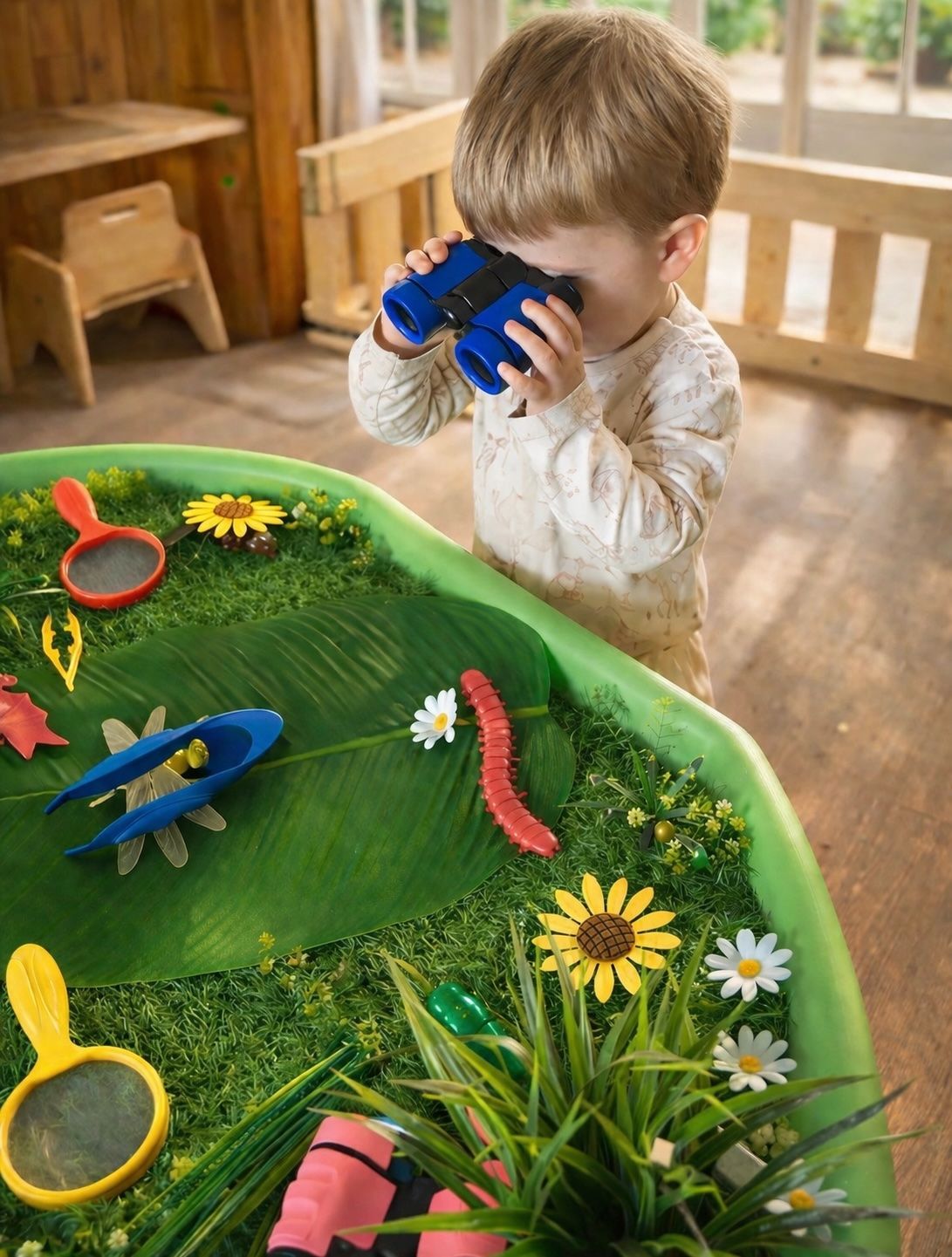 Child playing with toy insects in a green sensory tray indoors