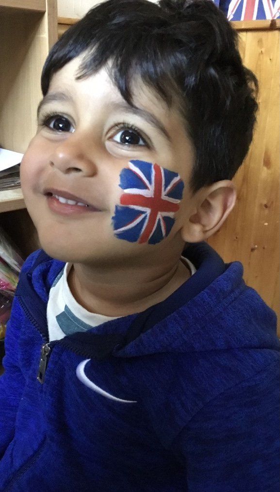 Smiling child with Union Jack face paint on cheek, wearing a blue hoodie
