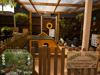Wooden memorial garden display with a bench, plaques, flowers, and a sign reading “Greens Corner.”